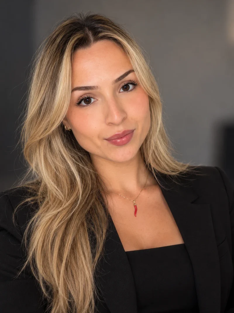Chiara Jirilio Mellace, Chief People Officer, with long blonde hair, in a black blazer, against a dark grey background.